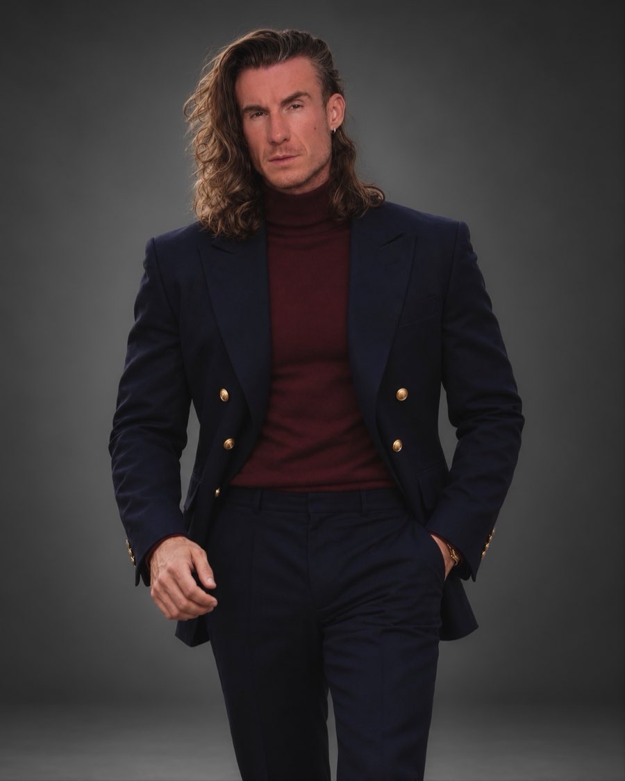 Adi Gheo in a navy double-breasted blazer and burgundy turtleneck