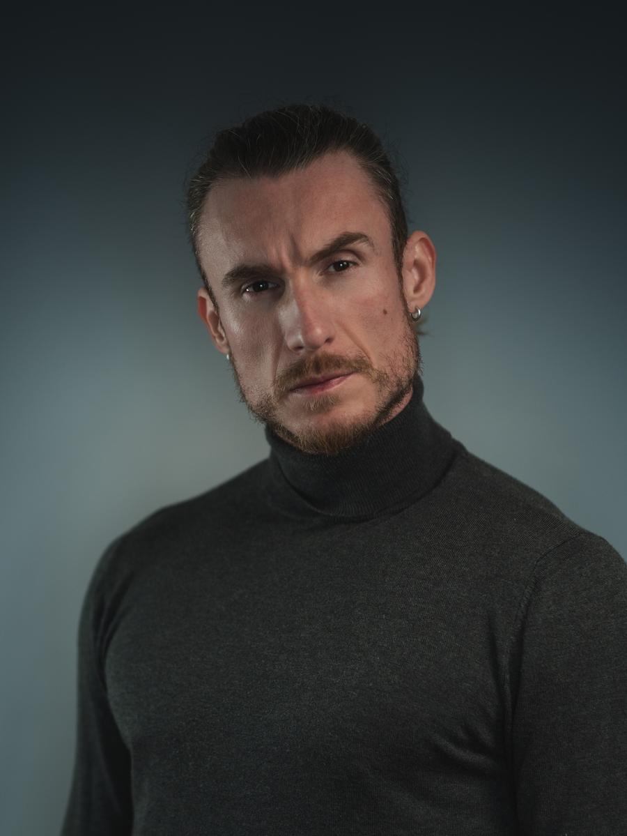 Adi Gheo in a charcoal turtleneck with his hair tied back