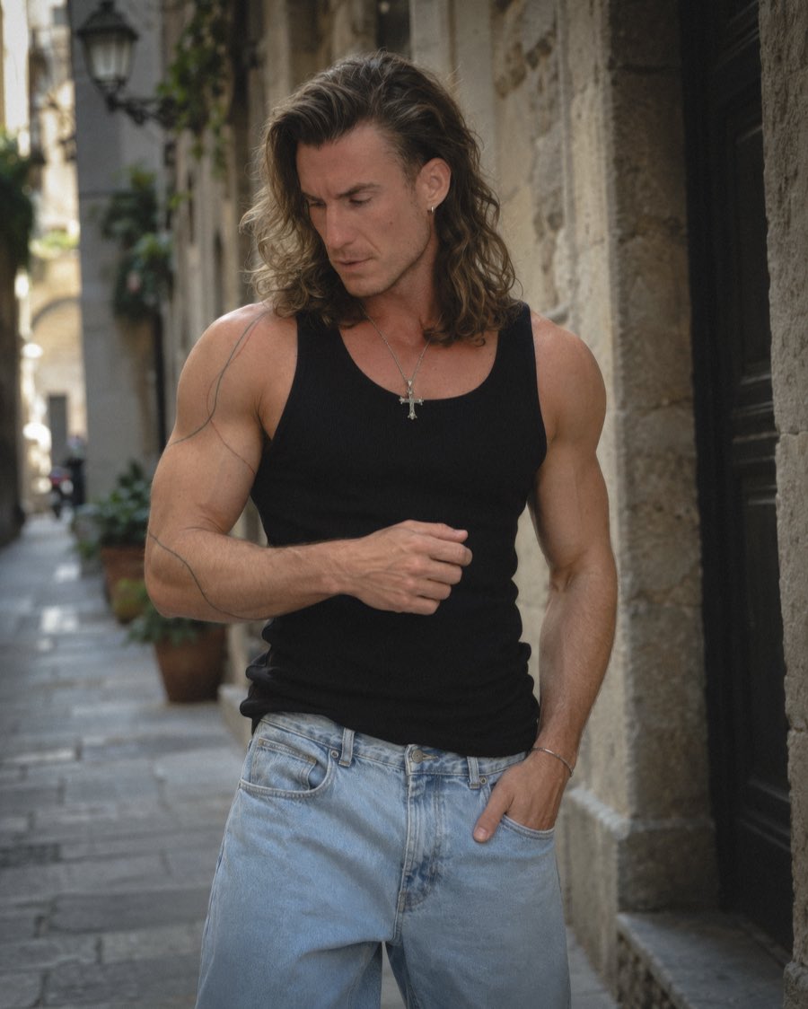 Adi Gheo in a black tank top and jeans on a narrow stone street