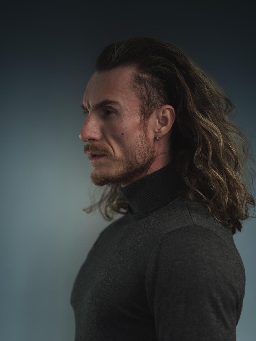 Left-facing profile of Adi Gheo with long hair and a charcoal turtleneck