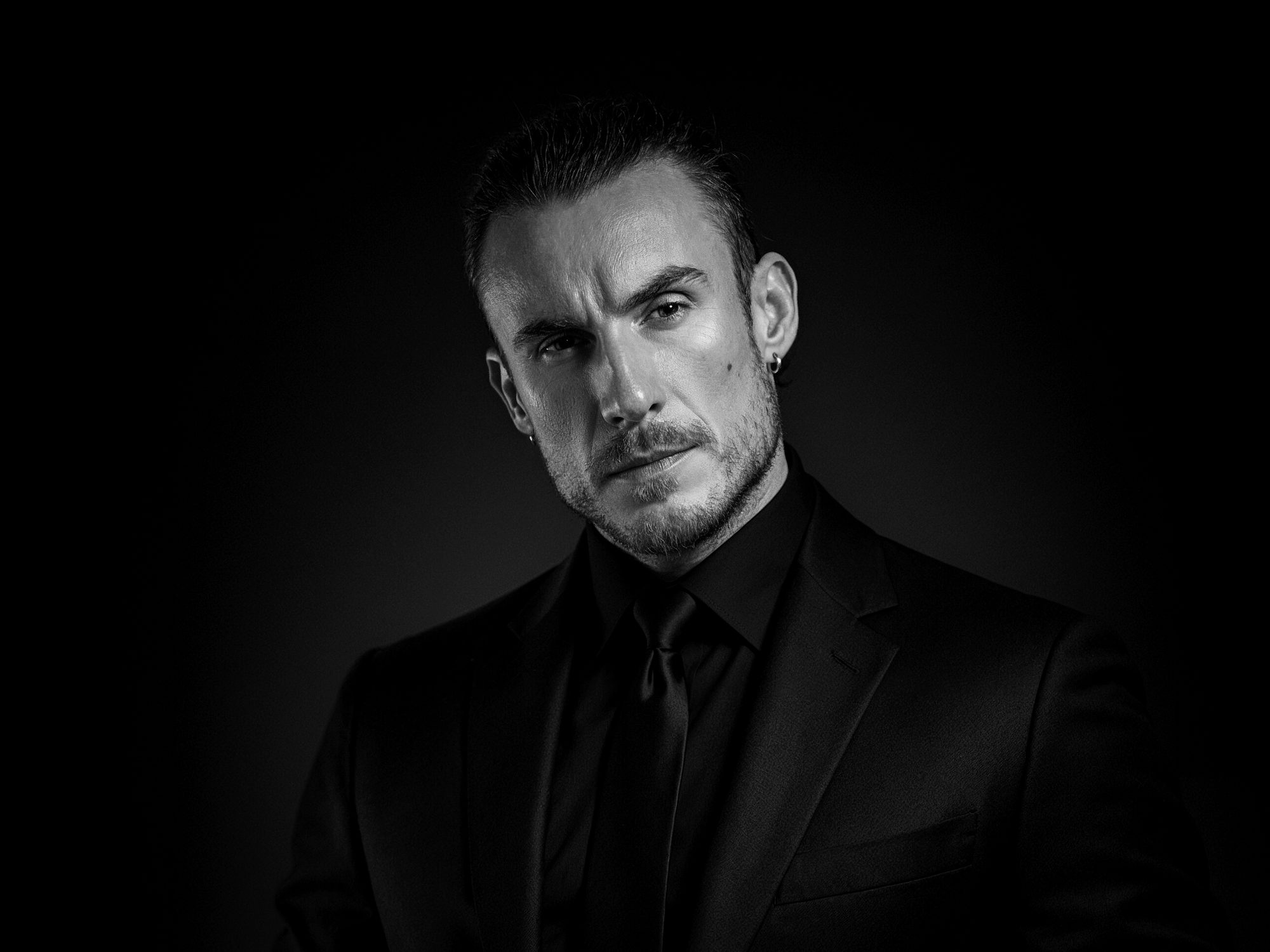 Black-and-white portrait of Adi Gheo in a black suit and tie on the homepage